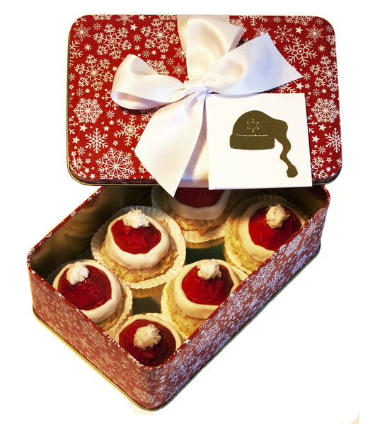 Image of coconut macaroons decorated to look like a Santa Hats in a festive holiday gift tin from Benedict Treats 