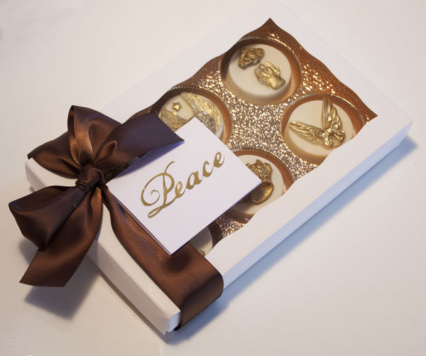 Image of a satin bow wrapped white gift box containing white chocolate covered oreos® with an ornate edible gold angel design on top as a cookie delivery gift from Benedict Treats