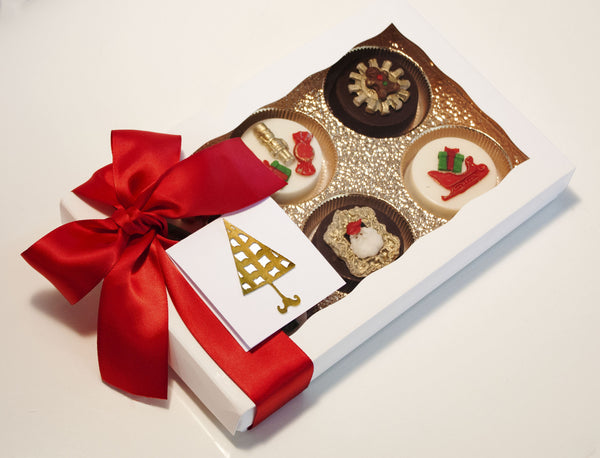 Image of a white gift box and red satin bow containing chocolate covered oreos® with a Santa's Workshop design as a Christmas cookie delivery gift from Benedict Treats