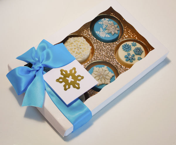 Image of nice white gift box with a blue satin bow containing chocolate covered oreos with a fun snowflake design as a holiday or christmas cookie delivery gift from Benedict Treats